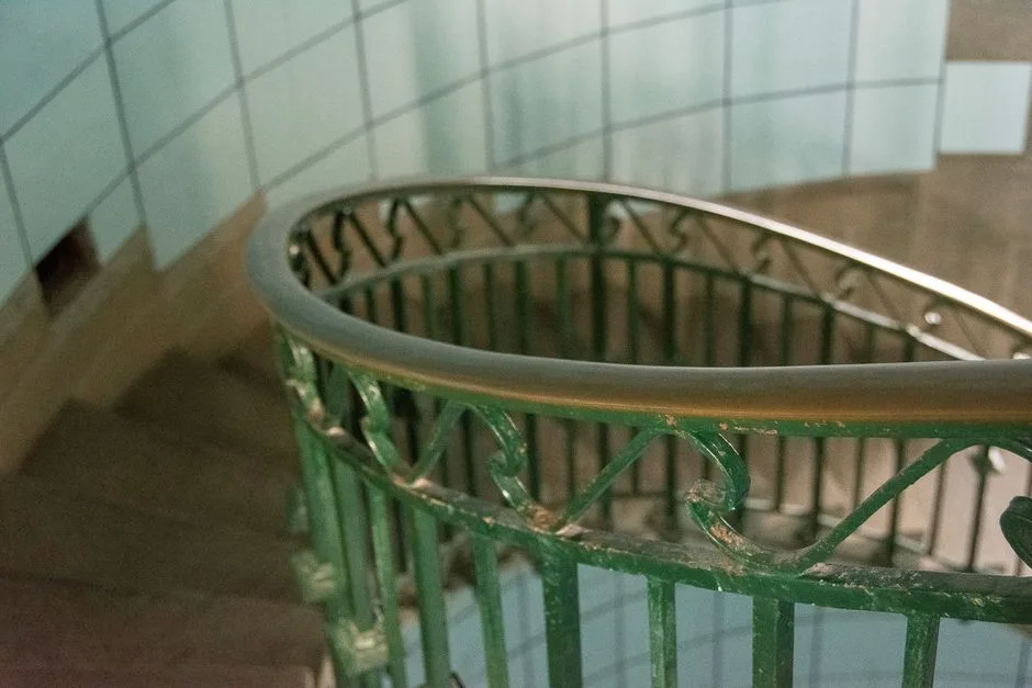 Treppenhaus im Altbau mit gefliesten Wänden und gusseisernem Geländer